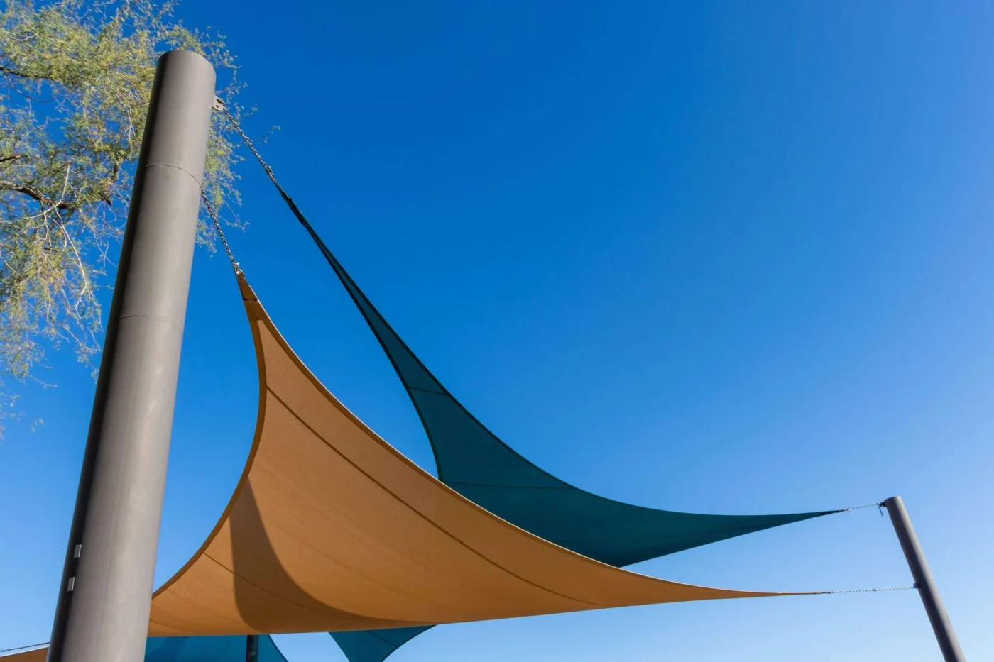 Twin sail shades against blue sky in San Pablo, CA by The Home Living Company