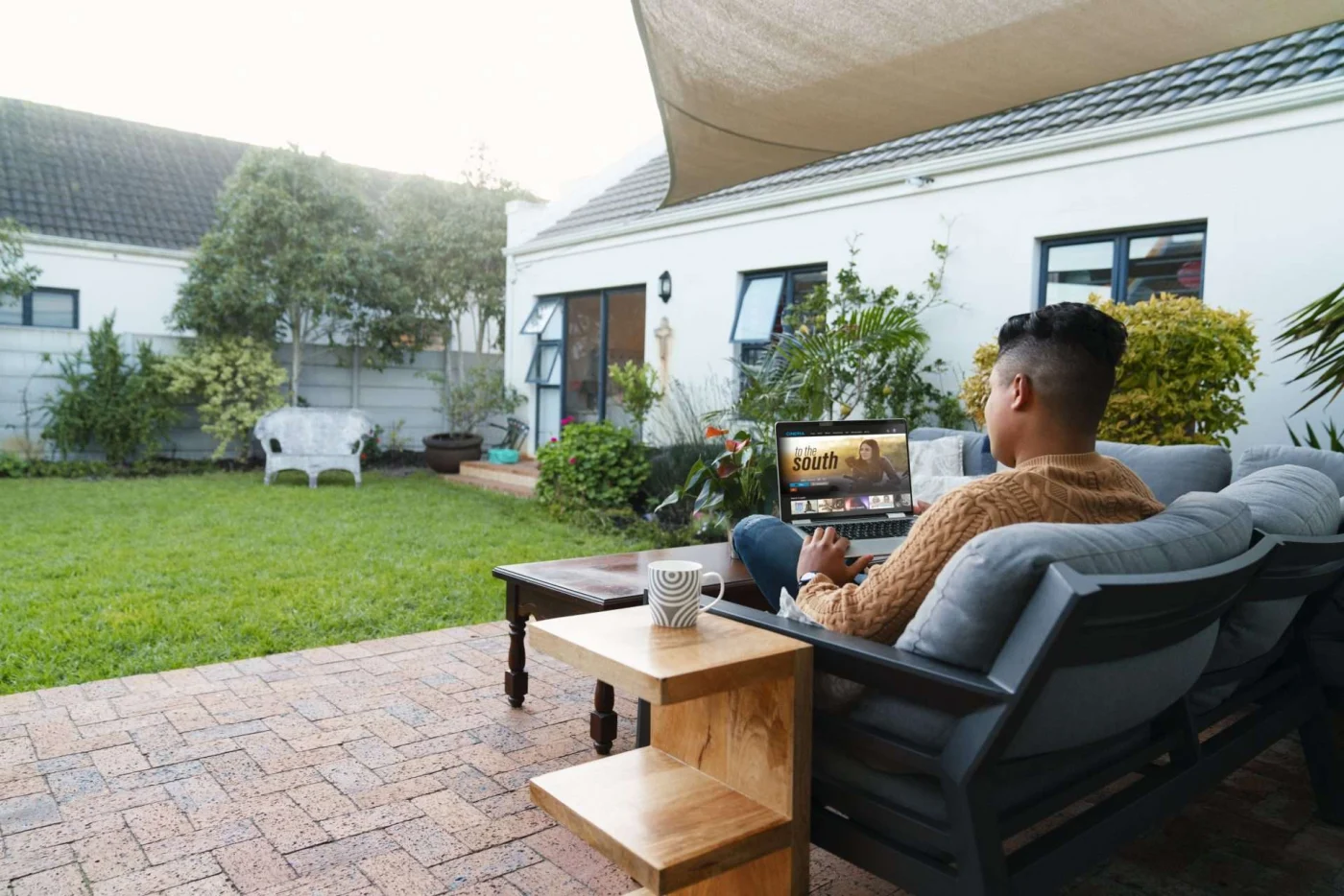 Man sitting in patio chair with sail shade above him in Lafayette, CA | The Home Living Company