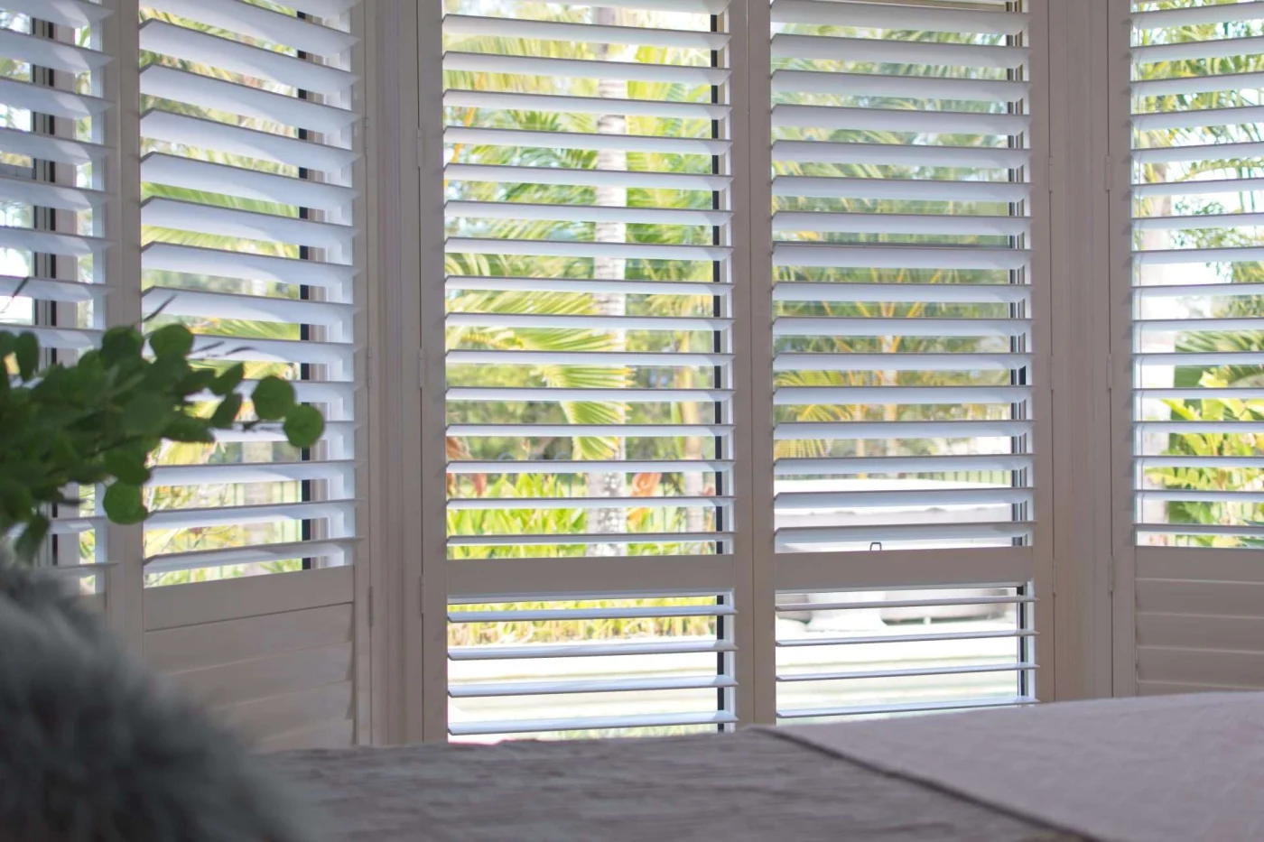 White plantation shutters in bedroom overlooking garden in San Pablo, CA by The Home Living Company