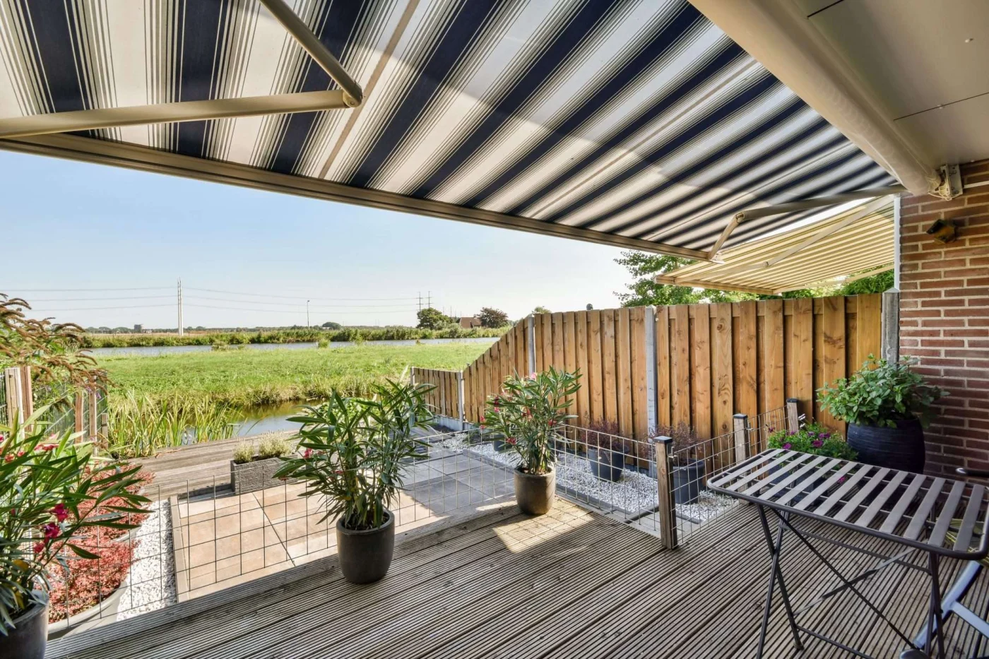 Neat Patio With Sitting Area Black and white striped retractable awning installed on patio of home