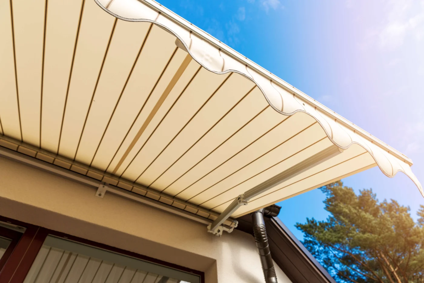 Awning Over Balcony Window Against Blue Sky White striped retractable awning over a Rossmore, CA patio