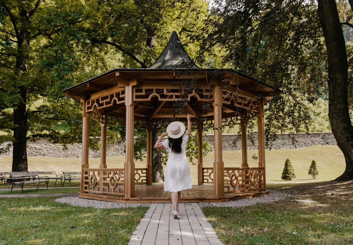 Gorgeous wooden gazebo in backyard that woman is walking towards