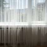 A spacious window in a Bay Area home with thin, gauzy curtains.